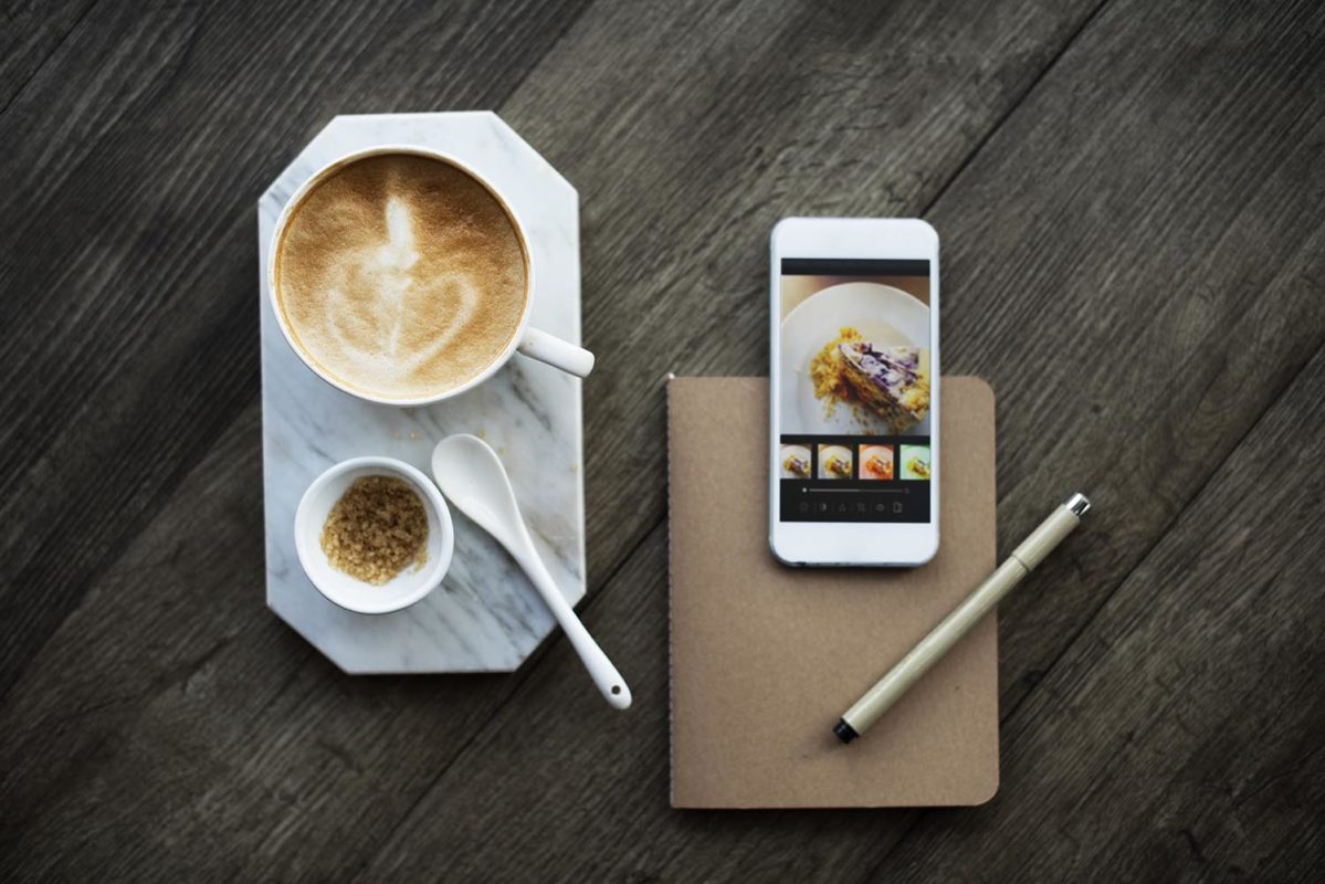 Aerial view of coffee cup and mobile phone on wooden table